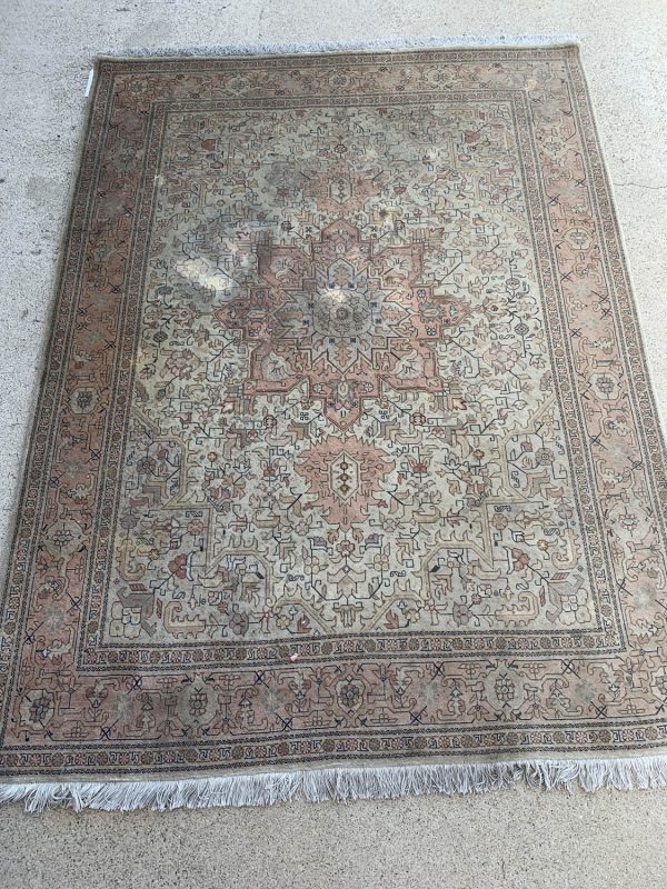 Vintage Persian rug with detailed floral motifs and a faded, elegant design.