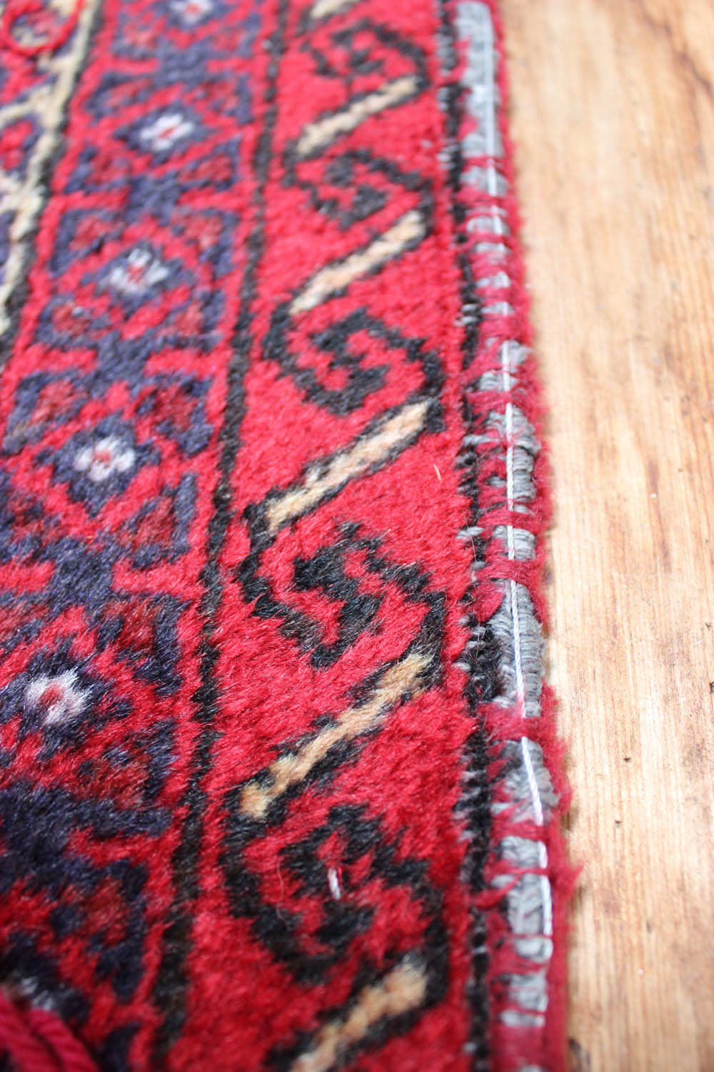 Vintage Zeytounian rug with repair stitches on a wooden floor.
