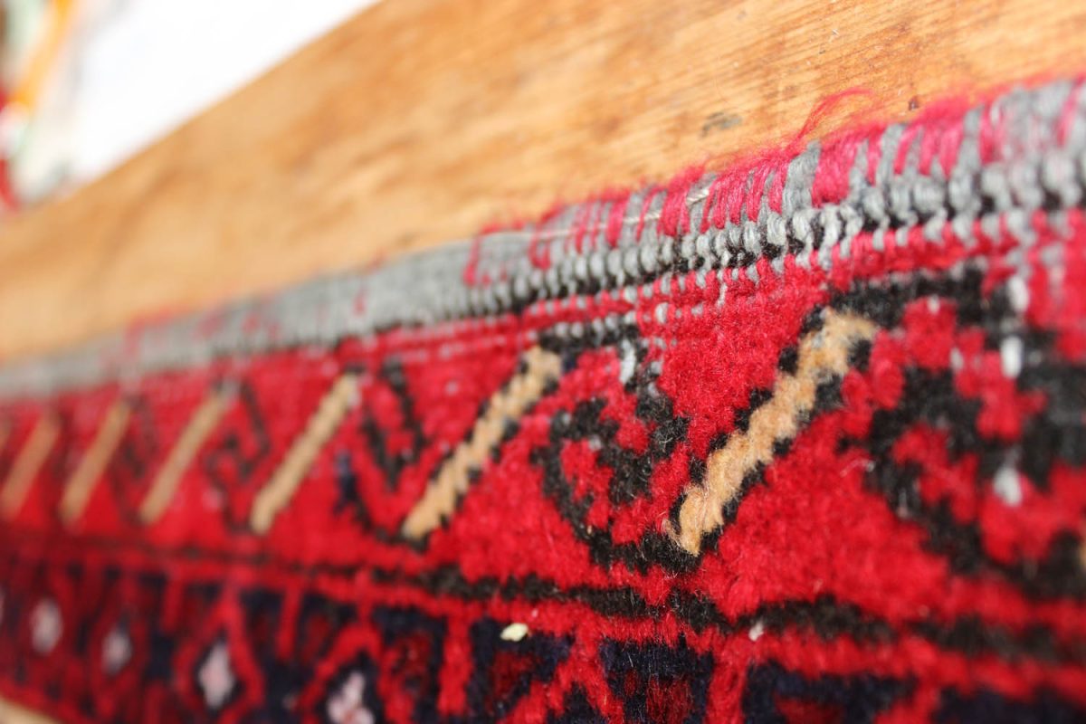 Vibrant red and black traditional rug with intricate patterns.