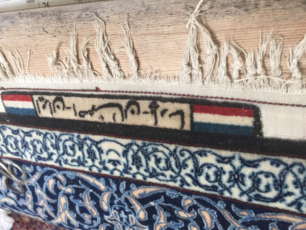 Frayed fringe and woven signature panel on the edge of a blue and cream rug