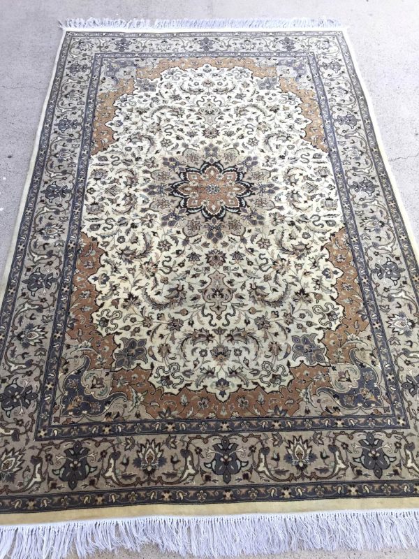Clean ivory medallion rug with apricot accents and white fringe laid out flat
